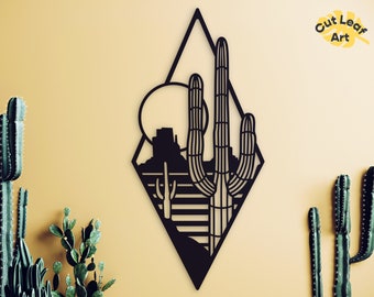 Può includere: Arte da parete in metallo nero con un paesaggio desertico con un cactus e una montagna a forma di diamante. L'arte è su uno sfondo giallo chiaro.