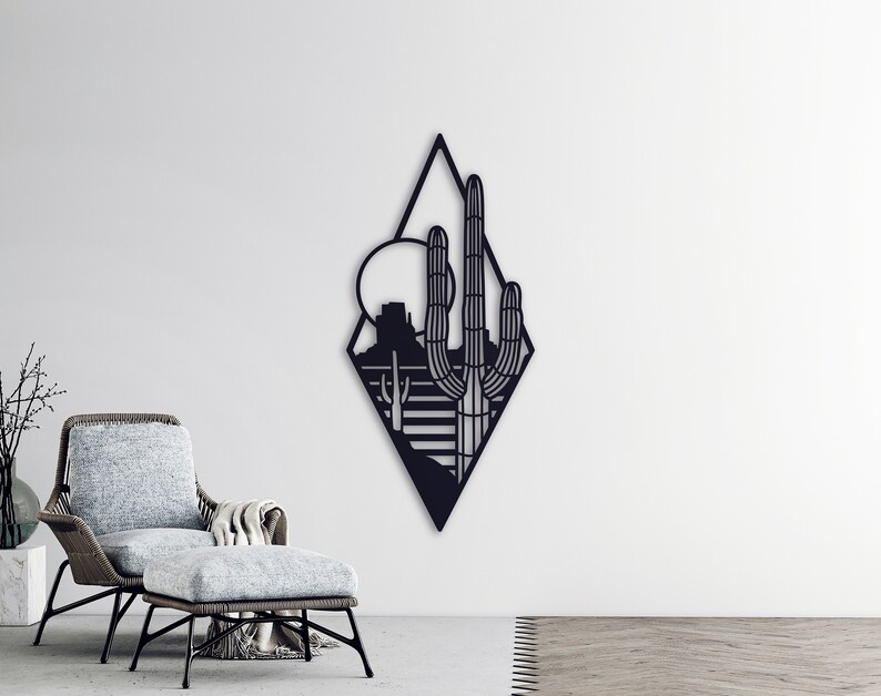 May include: Black metal wall art featuring a geometric diamond shape with a desert landscape silhouette inside. The design includes a cactus, mountains, and a sun.