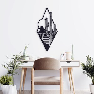 May include: Black metal wall art featuring a geometric desert landscape with a large cactus and a sun in the background.