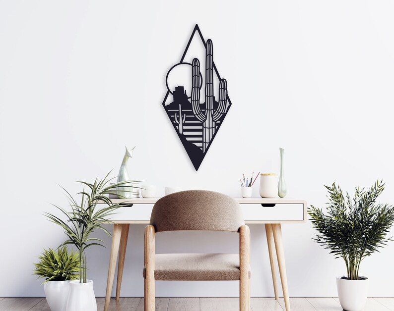 May include: Black metal wall art featuring a geometric desert landscape with a large cactus and a sun in the background.