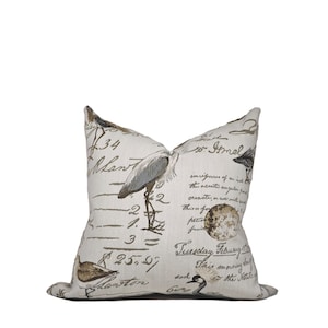May include: A white throw pillow with a brown and beige pattern of birds, handwritten text, and numbers. The text includes "Tuesday February" and "This morning early".