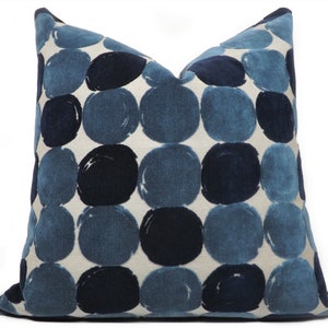 May include: A decorative throw pillow with a white background and a pattern of large blue and navy blue circles.