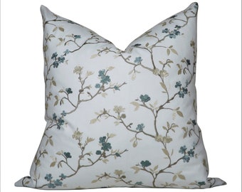 Könnte beinhalten: Ein weißes Kissen mit einem Blumenmuster mit blauen und braunen Blüten und Zweigen. Das Kissen ist aus einem weichen, strukturierten Stoff.