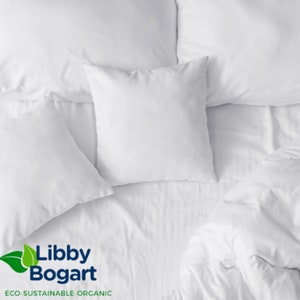 K&ouml;nnte beinhalten: Draufsicht auf ein Bett mit wei&szlig;er Bettw&auml;sche, einschlie&szlig;lich Kissen und einer Bettdecke. Die Kissen sind quadratisch und flauschig, und die Laken sind glatt. Das Bild enth&auml;lt das Libby Bogart-Logo mit dem Text "ECO-SUSTAINABLE-ORGANIC".