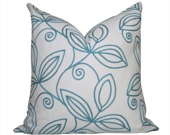 May include: A white pillow with a teal blue floral pattern. The pattern features stylized leaves and swirls.