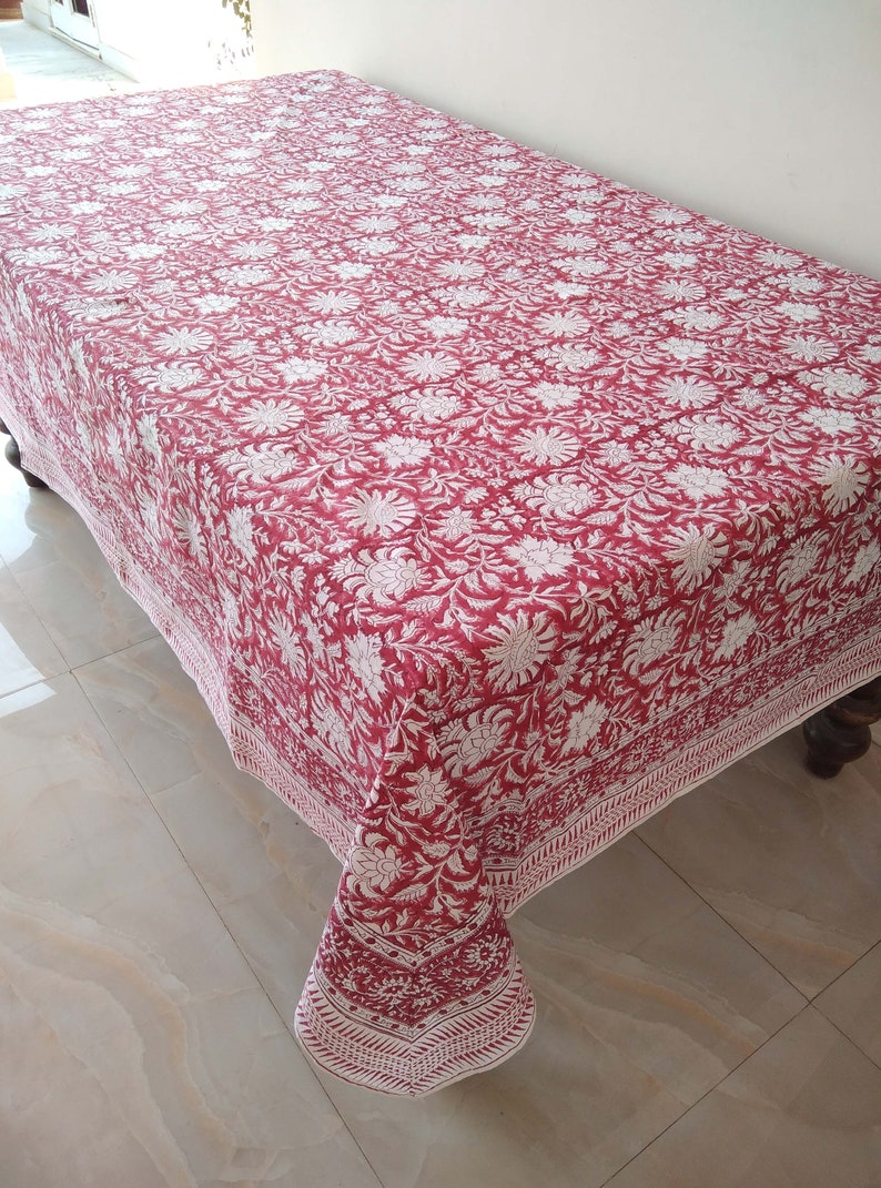 K&ouml;nnte beinhalten: Eine rote und wei&szlig;e Tischdecke mit Blumenmuster und wei&szlig;em Rand. Die Tischdecke ist aus Baumwolle und hat ein traditionelles indisches Design.