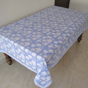 May include: A light blue tablecloth with a white floral pattern. The tablecloth is rectangular and has a white border.