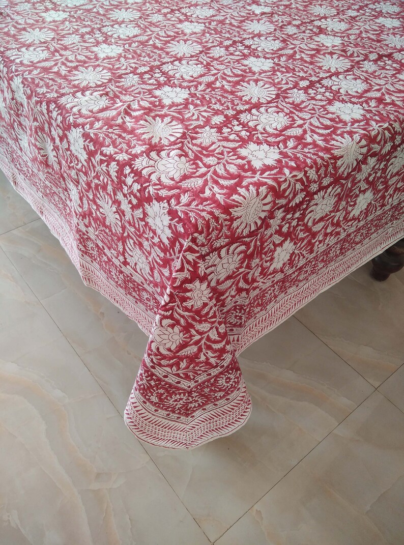 K&ouml;nnte beinhalten: Eine rote und wei&szlig;e Tischdecke mit Blumenmuster und wei&szlig;em Rand. Die Tischdecke ist aus Baumwolle und hat ein traditionelles indisches Design.