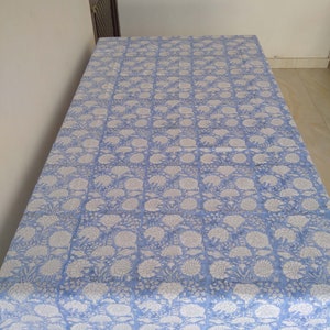May include: A blue and white floral tablecloth with a striped border. The tablecloth is made of cotton and is perfect for a dining table.