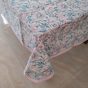 Peut inclure: Une nappe blanche avec un imprim&eacute; floral rose et vert. La nappe a une bordure ray&eacute;e rose et blanche.