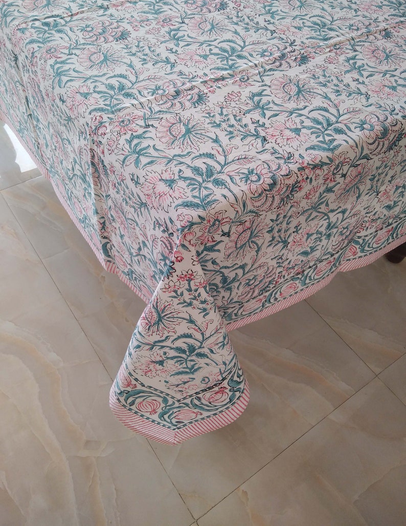 Peut inclure: Une nappe blanche avec un imprim&eacute; floral rose et vert. La nappe a une bordure ray&eacute;e rose et blanche.