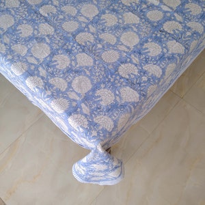 May include: A blue tablecloth with a white floral pattern. The tablecloth is made of cotton and has a soft, comfortable feel.