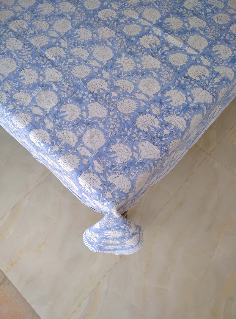 May include: A blue tablecloth with a white floral pattern. The tablecloth is made of cotton and has a soft, comfortable feel.