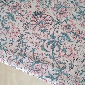 Peut inclure: Un tissu blanc avec un motif floral dans les tons rose et turquoise. Le tissu a un design indien traditionnel avec des d&eacute;tails complexes.