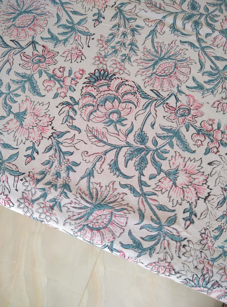 Peut inclure: Un tissu blanc avec un motif floral dans les tons rose et turquoise. Le tissu a un design indien traditionnel avec des d&eacute;tails complexes.