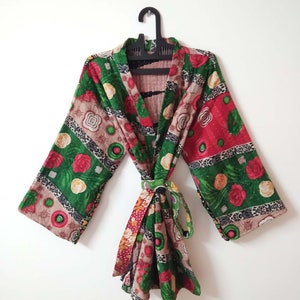 Pode incluir: Um quimono com padrão floral verde, vermelho e marrom, manga comprida e cinto para amarrar.