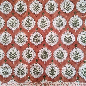 Pu&ograve; includere: Un tessuto rosso con un motivo floreale bianco e verde. Il tessuto ha un bordo con un motivo simile su scala pi&ugrave; piccola.