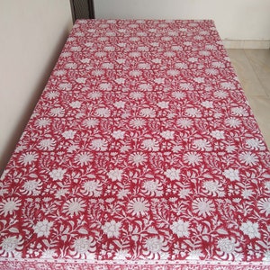 K&ouml;nnte beinhalten: Eine rote und wei&szlig;e Tischdecke mit Blumenmuster und wei&szlig;em Rand. Die Tischdecke ist aus Baumwolle und hat ein traditionelles indisches Design.