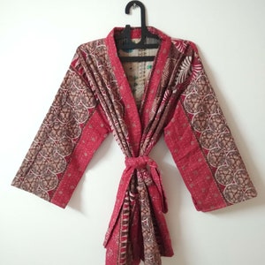 May include: A red and brown patterned kimono robe with a tie belt. The robe has a traditional Japanese style with long sleeves and a V-neck.
