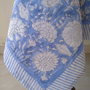 May include: A blue and white tablecloth with a floral pattern. The tablecloth has a white border with blue stripes.
