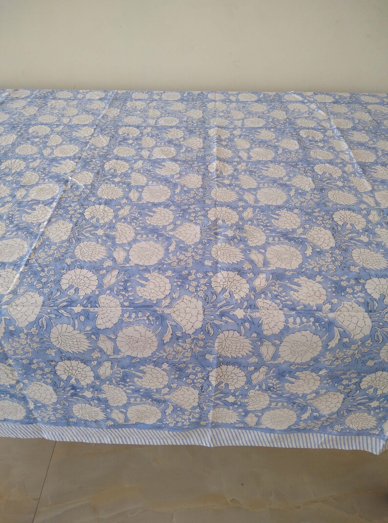 May include: A blue and white floral patterned tablecloth with a white and blue striped border.