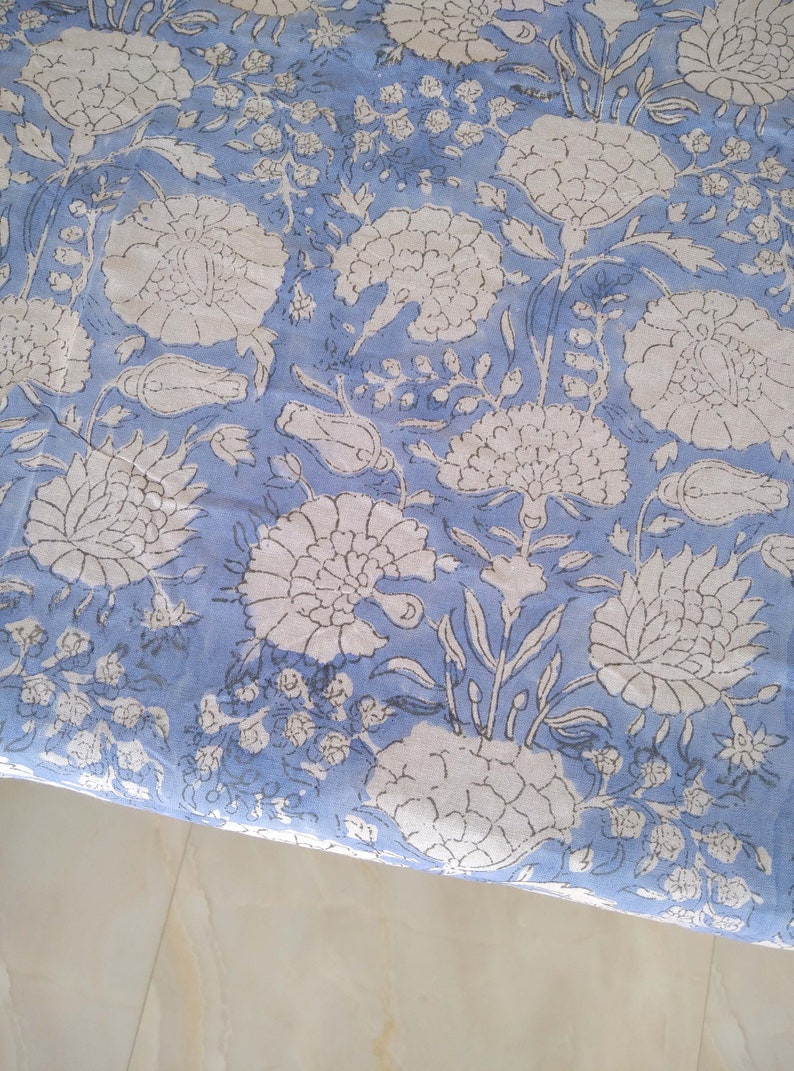 May include: A blue fabric with a white floral pattern. The fabric has a traditional Indian design with intricate details.