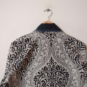 K&ouml;nnte beinhalten: Ein grauer Blazer mit schwarzem Muster und einem dunkelblauen Kragen.