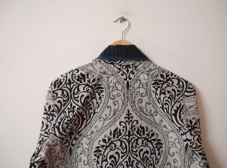 K&ouml;nnte beinhalten: Ein grauer Blazer mit schwarzem Muster und einem dunkelblauen Kragen.