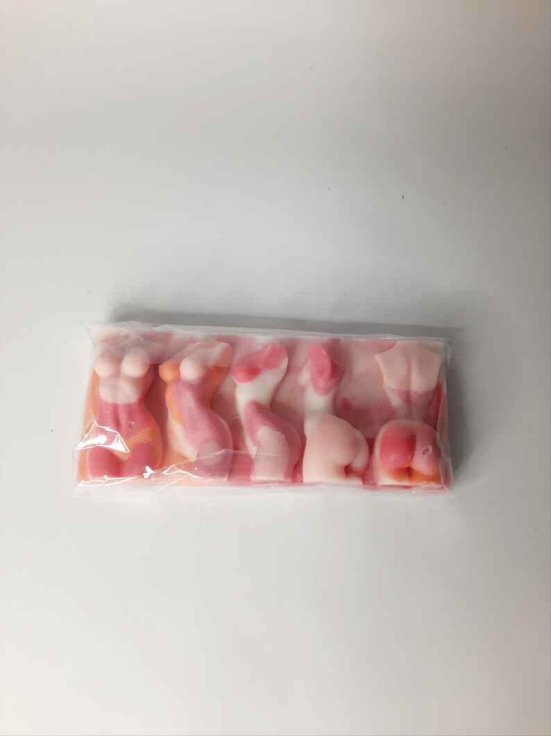 Puede incluir: Un paquete de gominolas rosadas y blancas con forma de figuras humanas.