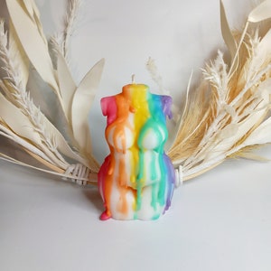 Puede incluir: Una vela de color arcoíris con forma de torso humano. La vela gotea cera, creando un diseño colorido y abstracto.