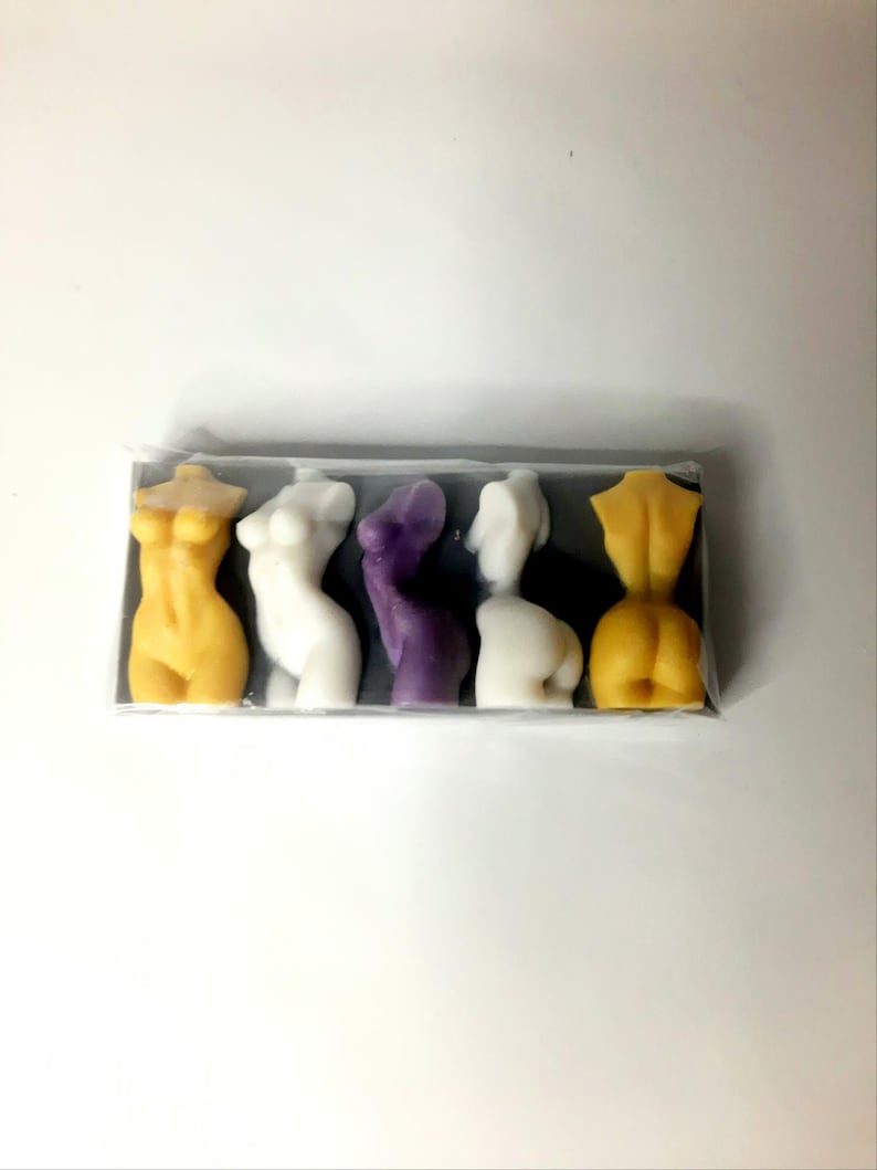 Puede incluir: Cinco peque&ntilde;as figuras esculpidas de torsos humanos en un paquete de pl&aacute;stico transparente. Las figuras est&aacute;n dispuestas en fila y est&aacute;n hechas de un material liso y ceroso. Los colores son amarillo, blanco, morado, blanco y amarillo.