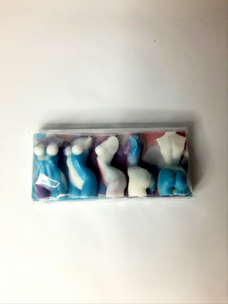 Puede incluir: Cinco barras de jab&oacute;n coloridas, abstractas, con forma humana en una bolsa de pl&aacute;stico transparente. Las barras de jab&oacute;n son en tonos de azul, blanco y morado.