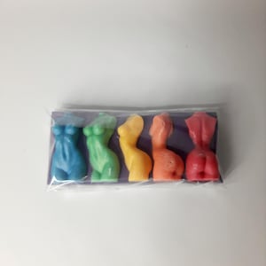 Puede incluir: Cinco peque&ntilde;as figuritas de colores con forma humana en un esquema de colores arco&iacute;ris. Las figuritas est&aacute;n dispuestas en fila sobre un fondo morado.