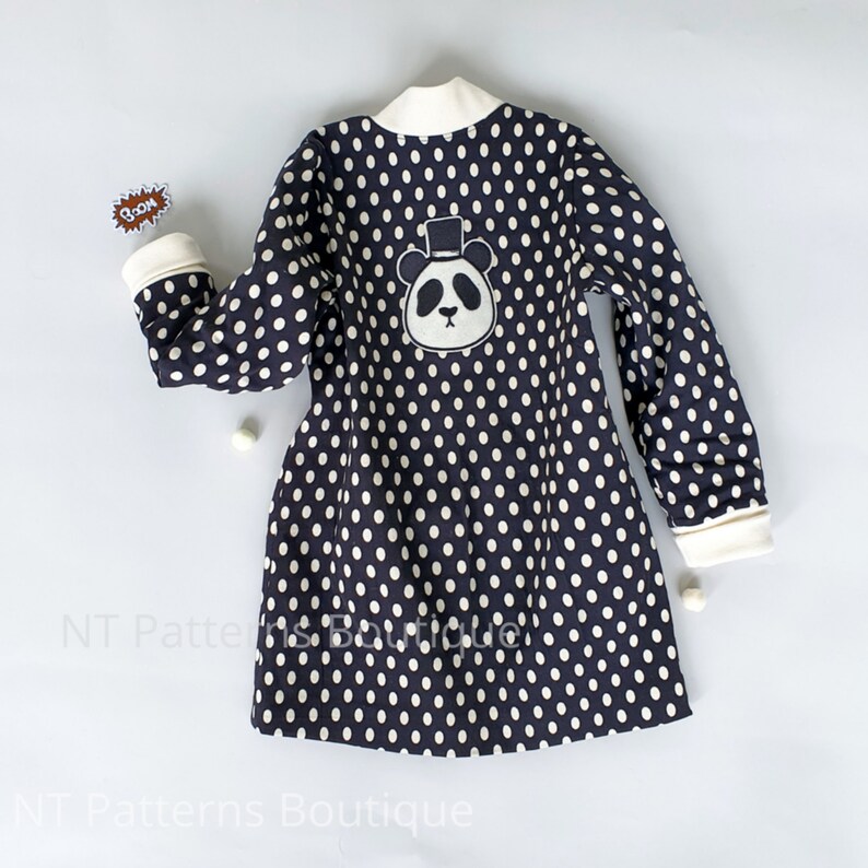 May include: A black and white polka dot dress with long sleeves and a white collar. The dress has a panda bear wearing a top hat embroidered on the back.