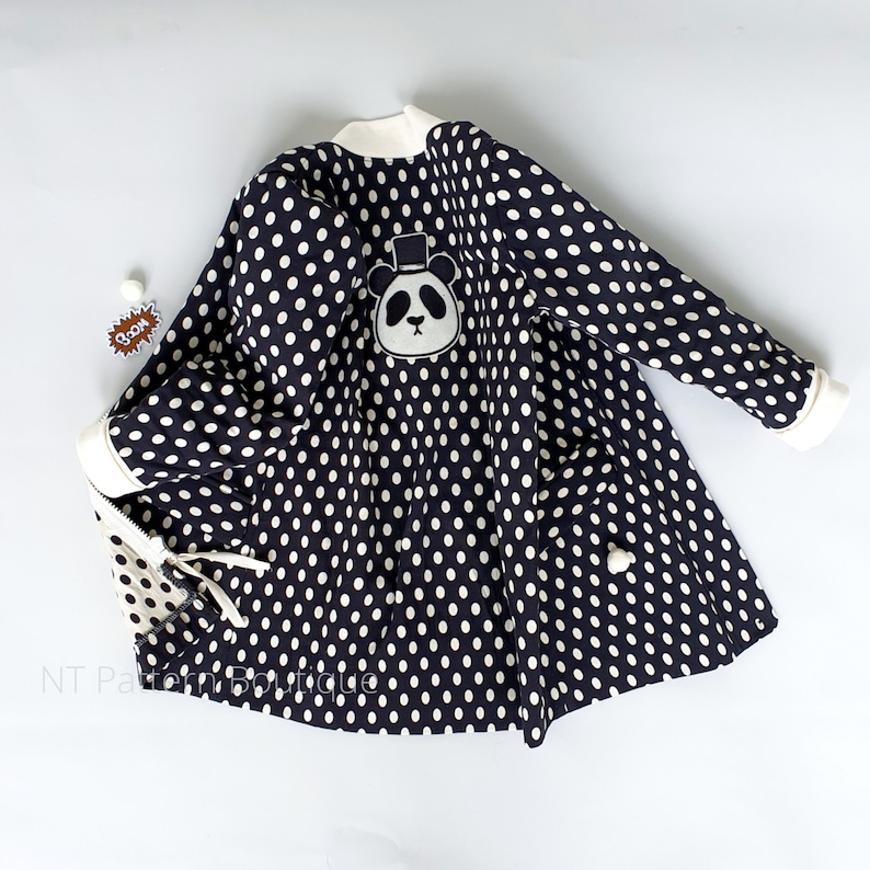 May include: Black and white polka dot dress with a panda bear applique. The dress has a white collar and long sleeves.
