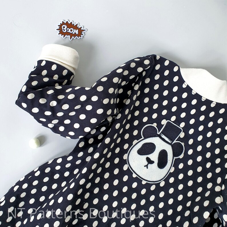 May include: Black and white polka dot fabric with a white panda bear applique wearing a black top hat. The fabric has the text "BOOM!" on it.