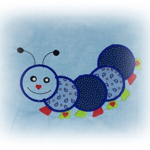 May include: A blue and white patchwork caterpillar with a smiling face, red hearts, and green leaves. The caterpillar is made of fabric and is sewn together.