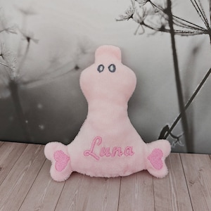 Könnte beinhalten: Rosa Plüschtier in Form einer Person mit herzförmigem Schwanz und herzförmigem Kopf. Das Spielzeug hat gestickte Augen und der Name "Luna" ist auf der Vorderseite gestickt.
