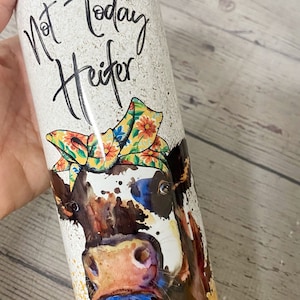 This stainless steel tumbler says not today heifer on one side with a cow wearing a bandana and on the other side it says not my pasture not my bullshit, the bottom is a yellowish gold.  these are wonderful skinny tumblers