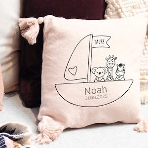 K&ouml;nnte beinhalten: Ein rosa Kissen mit einem wei&szlig;en Segelboot-Design und dem Text "Taufe Noah 31.08.2025". Das Segelboot hat drei Tiere darauf: eine Giraffe, ein Koala und ein Zebra.
