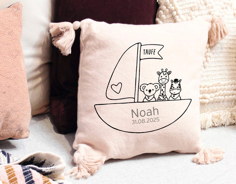 K&ouml;nnte beinhalten: Ein rosa Kissen mit einem wei&szlig;en Segelboot-Design und dem Text "Taufe Noah 31.08.2025". Das Segelboot hat drei Tiere darauf: eine Giraffe, ein Koala und ein Zebra.