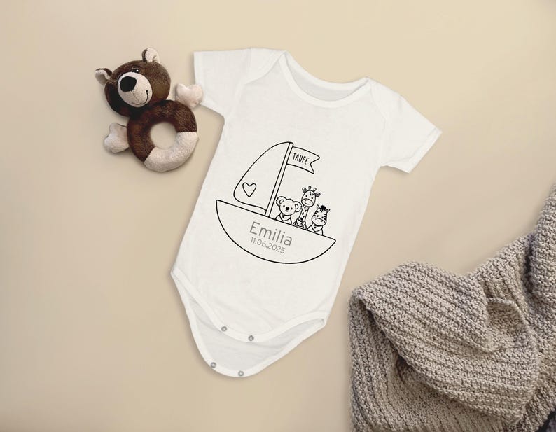 K&ouml;nnte beinhalten: Wei&szlig;er Babybody mit einer schwarz-wei&szlig;en Illustration eines Segelboots mit einem B&auml;ren, einer Giraffe und einem Zebra darauf. Der Text "Taufe" steht auf dem Segel und "Emilia 11.06.2023" steht unter dem Boot.