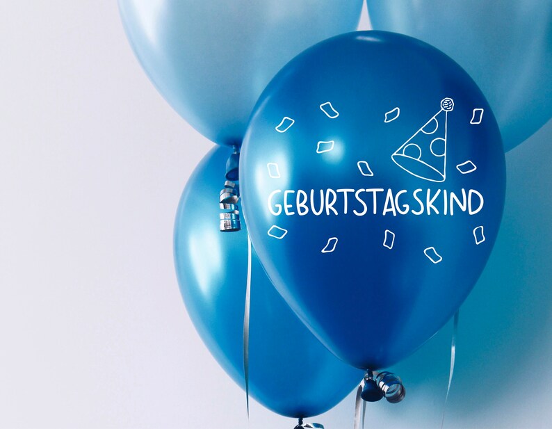 May include: Three blue balloons with a white party hat and the text "Geburtstagskind" on one balloon.