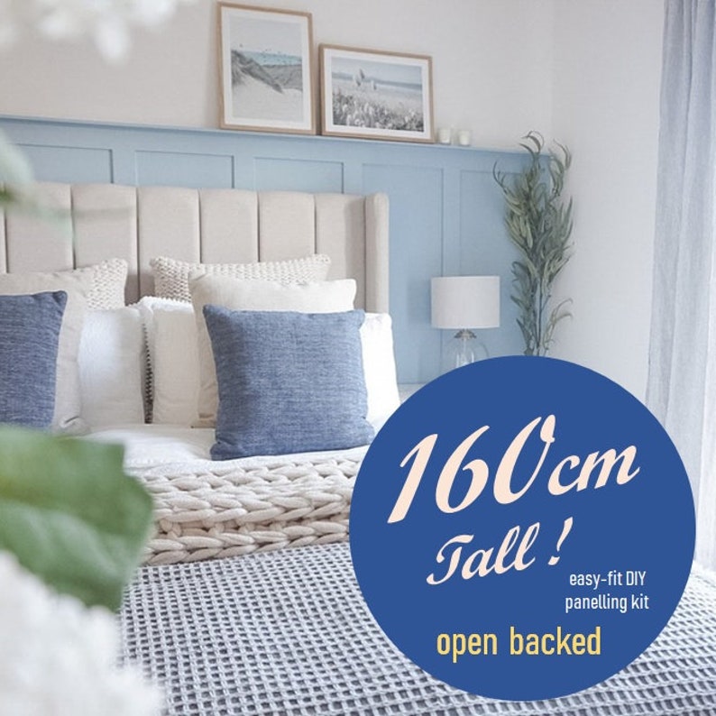 Op de afbeelding: Een slaapkamer met een wit hoofdbord en blauwe beddengoed. De muur achter het bed is lichtblauw geverfd en heeft een witte plank met twee ingelijste foto's. Een blauwe cirkel met witte tekst zegt "160 cm hoog! eenvoudig te installeren doe-het-zelf wandbekledingset met open achterkant".
