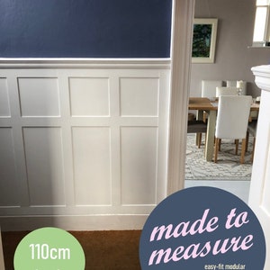 May include: White paneled wall with a dark blue top and a light brown carpet. The wall is 110cm high and the text "made to measure easy-fit modular panelling system back-boarded" is on a blue circle.