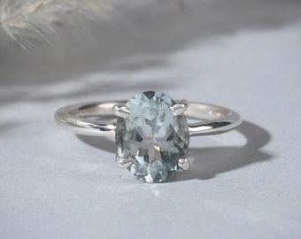 May include: A silver ring with a light blue oval gemstone.