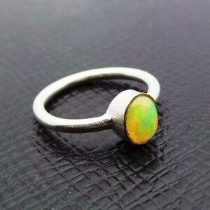 May include: A silver ring with a round, pale green opal gemstone.