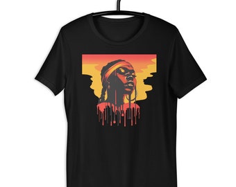 May include: Black t-shirt with a graphic portrait of a woman wearing a headband and hoop earrings. The artwork uses orange, red, and yellow hues, with a dripping paint effect. The t-shirt is displayed on a black hanger.