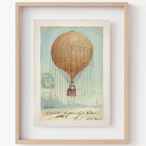 Może przedstawiać: Winyetkowe akwarelowe przedstawienie balonu na gorące powietrze zatytułowane "Le Géant Va Voler 1863". Balon jest brązowy i ma wiklinowy kosz. Ilustracja jest oprawiona w jasną drewnianą ramę.