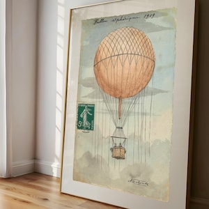 May include: Framed vintage print of a hot air balloon. The artwork depicts an orange balloon with a woven basket. A green postage stamp is visible, along with the text "Ballon Spherique 1909."